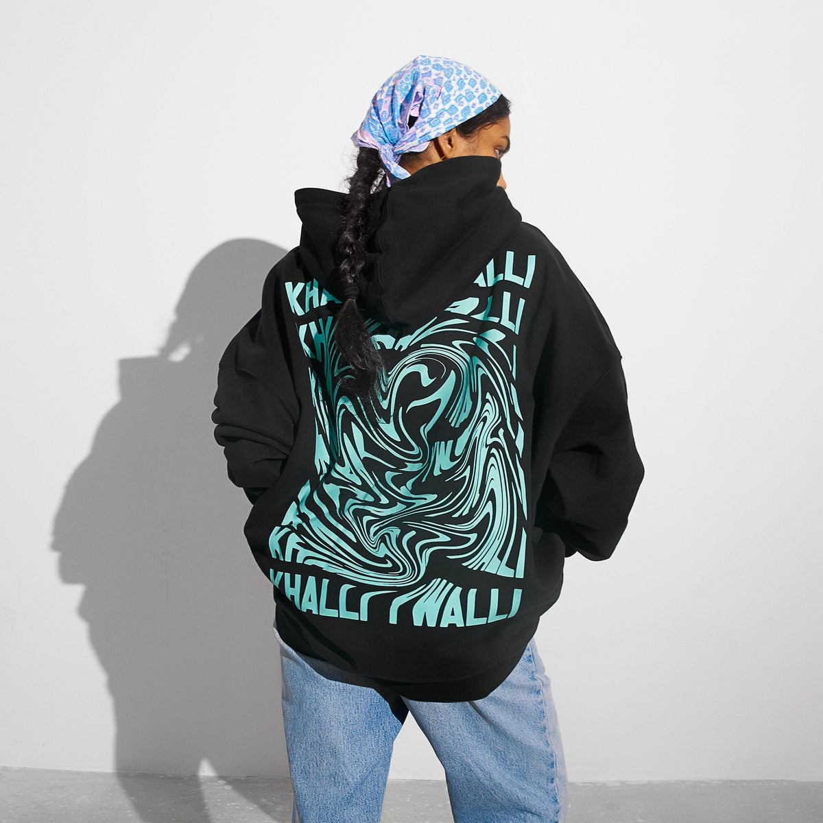 Khalli Yiwalli hoodie in black with neon mint Arabic print, worn front view